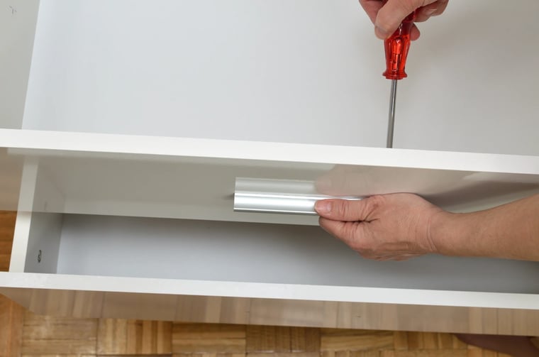 Man fitting drawer pull handle with a screwdriver