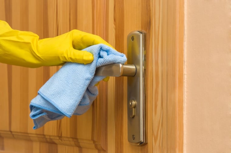 Cleaning a door handle with blue microfibre cloth