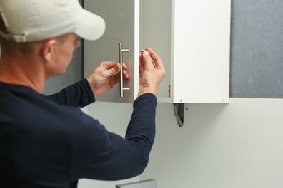 Man installing pull handles onto a cabinet